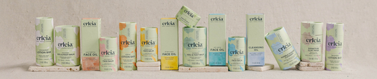Erleia’s full skincare collection displayed in a row, featuring face oils, balms, cleansers, and lotion bars in eco-friendly packaging.