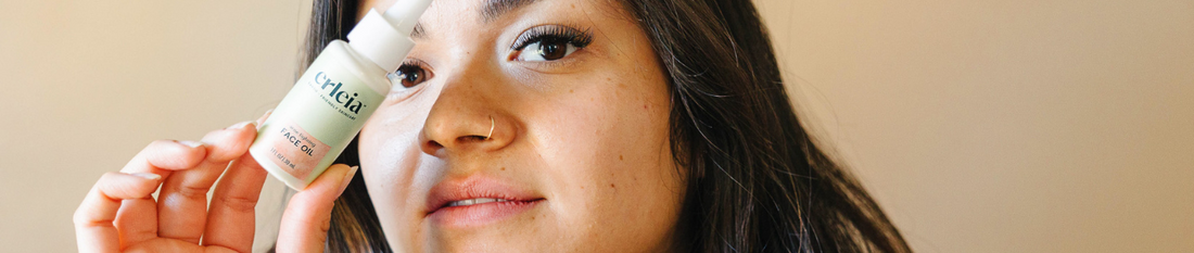 ChatGPT said: A woman holding Erleia Acne Fighting Face Oil close to her face.