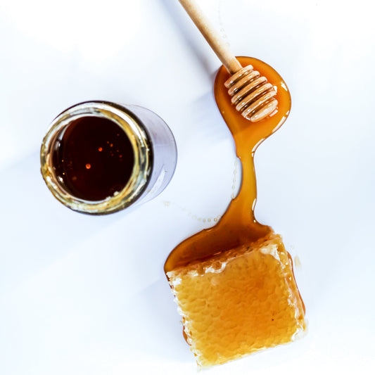 Overhead shot of a jar of honey, a honey spoon and honeycomb