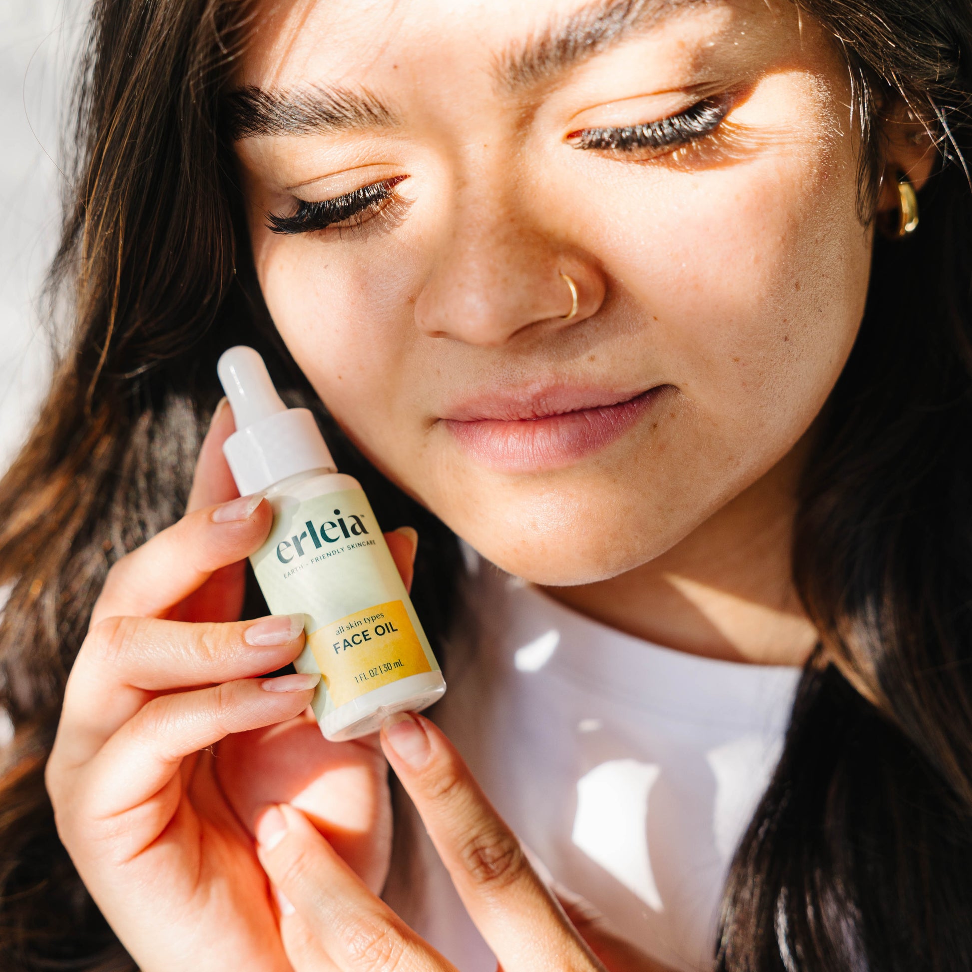 A light skinned Latina woman holding an Erleia All Skin Types Face Oil