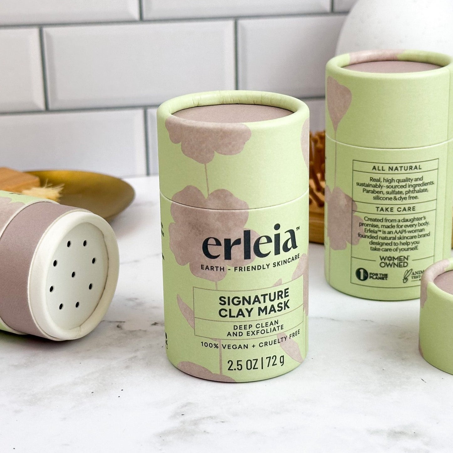 3 Erleia Signature Clay Masks on a bathroom counter, one is open showing the shaker dispenser top