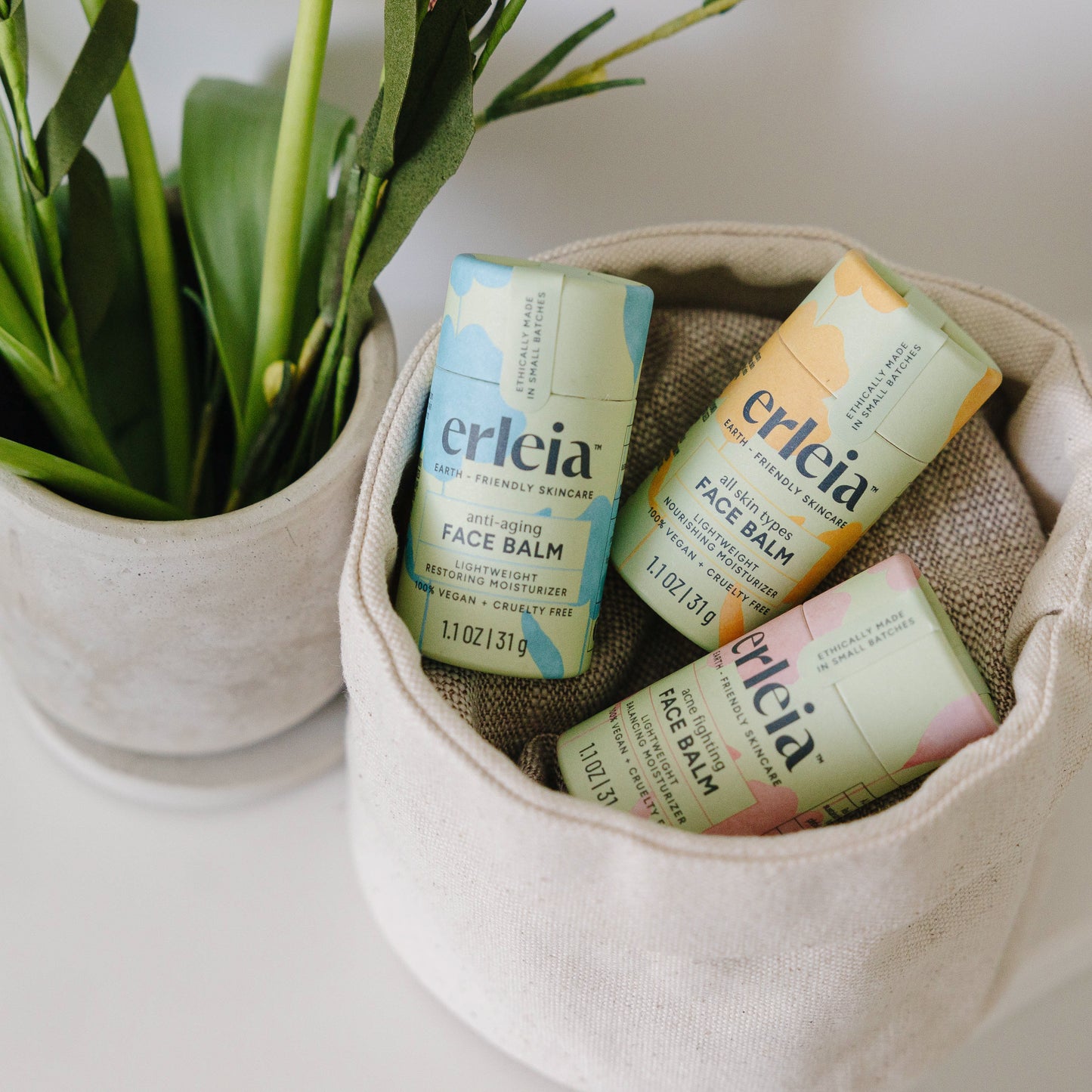 3 Erleia Face Balms - in all 3 varieties: anti-aging, all skin types, acne fighting - in a fabric basket on a white counter