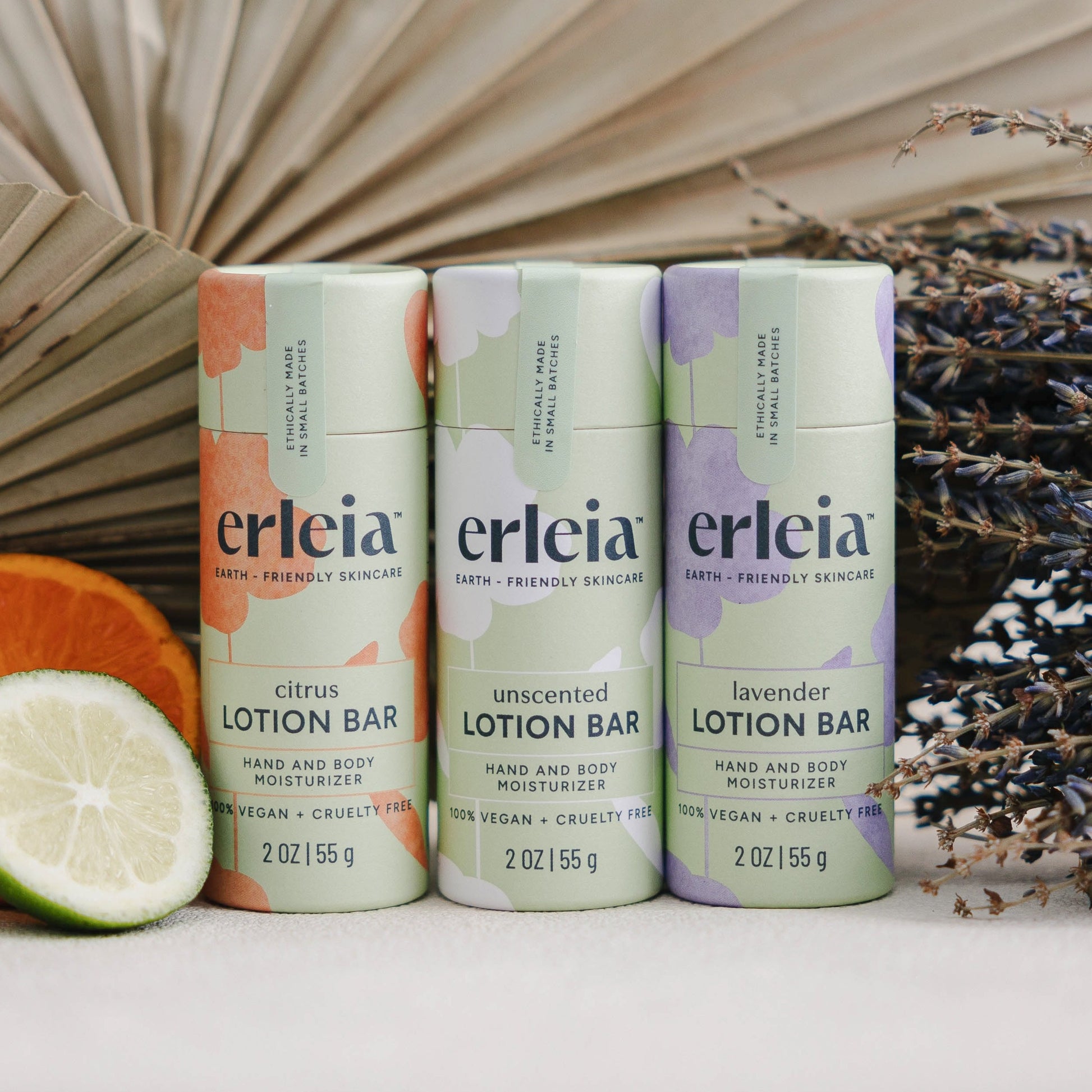 3 Erleia Lotion Bars in 3 scents from left to right: citrus, unscented and lavender, in front of a dried palm leaf, citrus slices and dried lavender