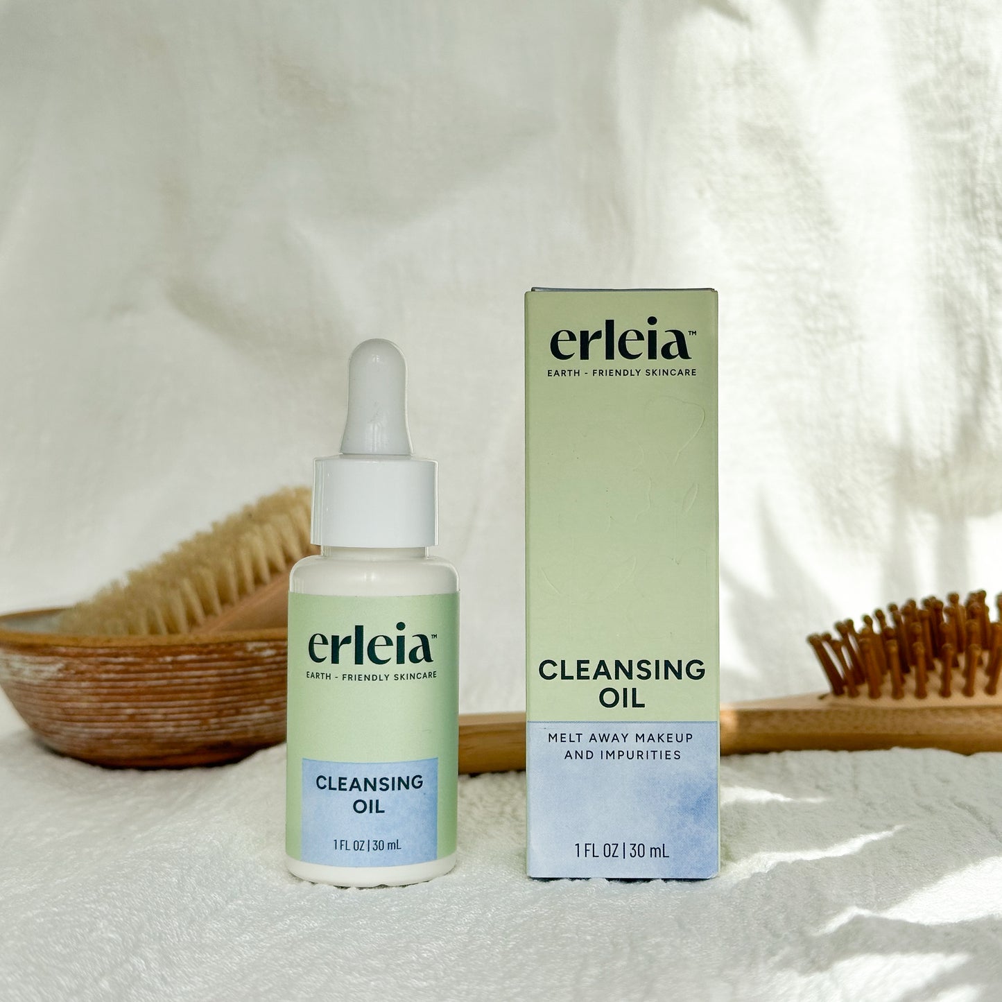 Erleia Cleansing Oil Bottle and Box on a white warm background with shadows and bathroom items in the background