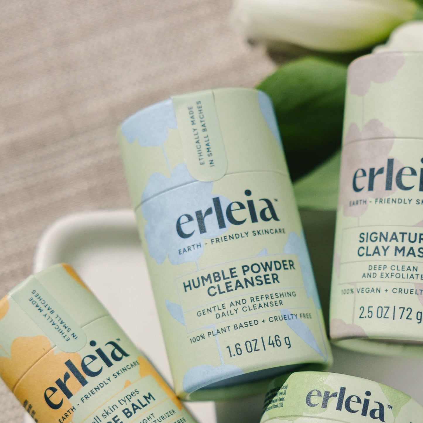 An Erleia Humble Powder Cleanser next to other Erleia products on a white dish