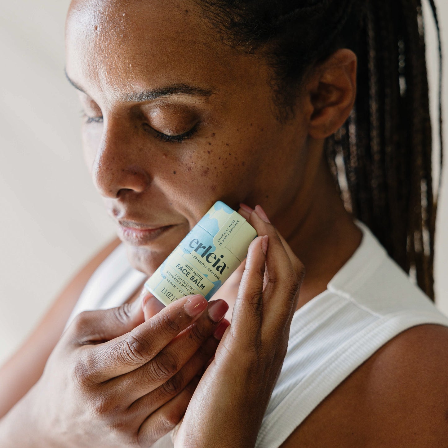 A Black woman holding an Erleia anti-aging Face Balm to her face