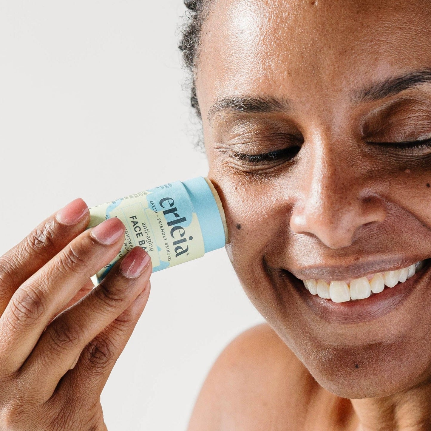 A Black woman applying Erleia anti-aging Face Balm to her skin