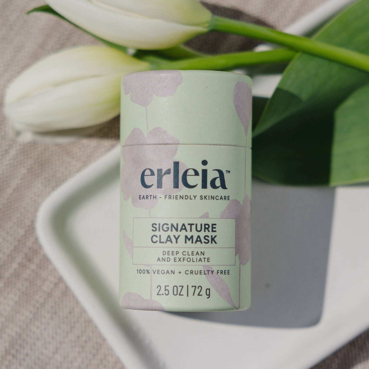 Erleia Signature Clay Mask on a white dish with flowers