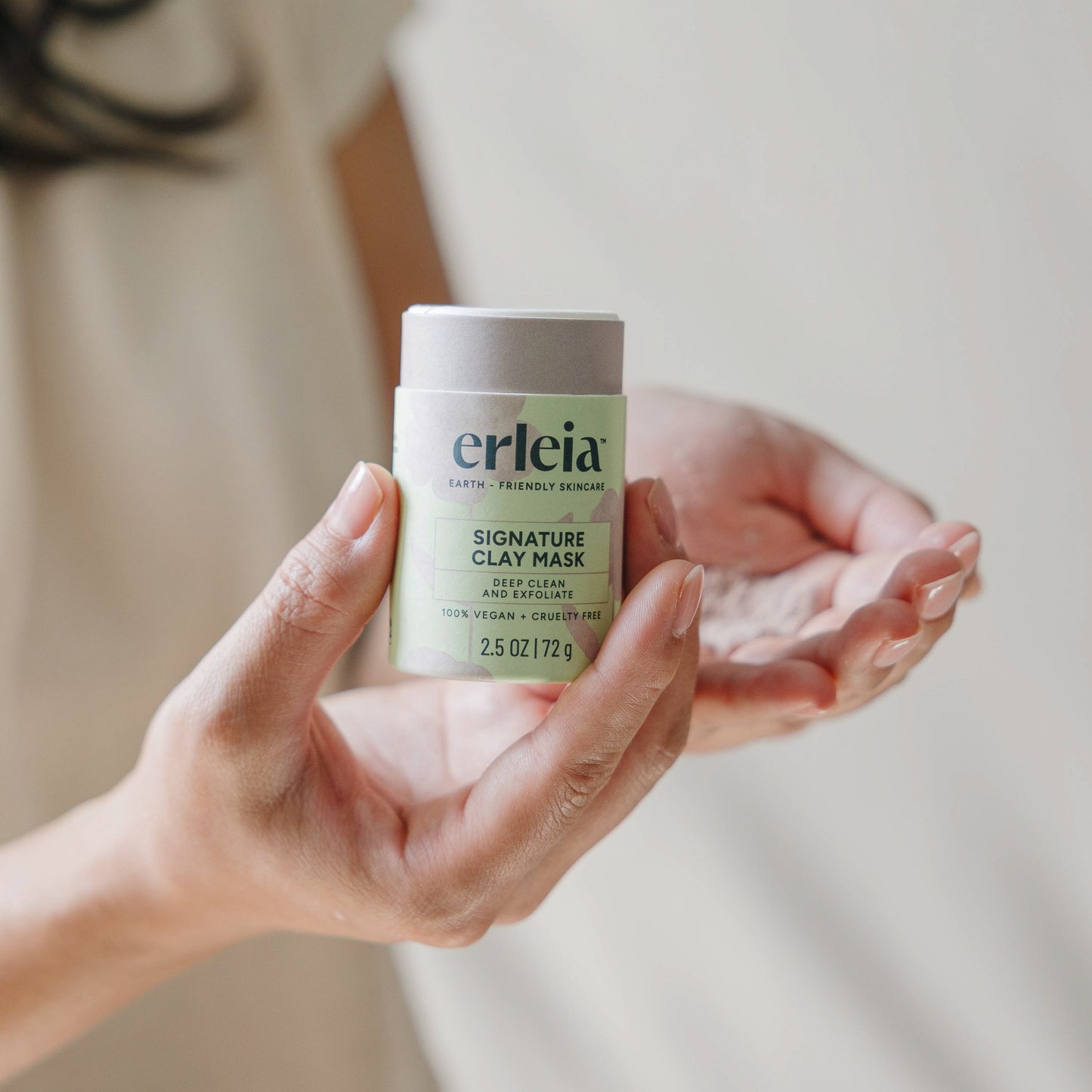 East Asian hands holding an open Erleia Signature Clay Mask