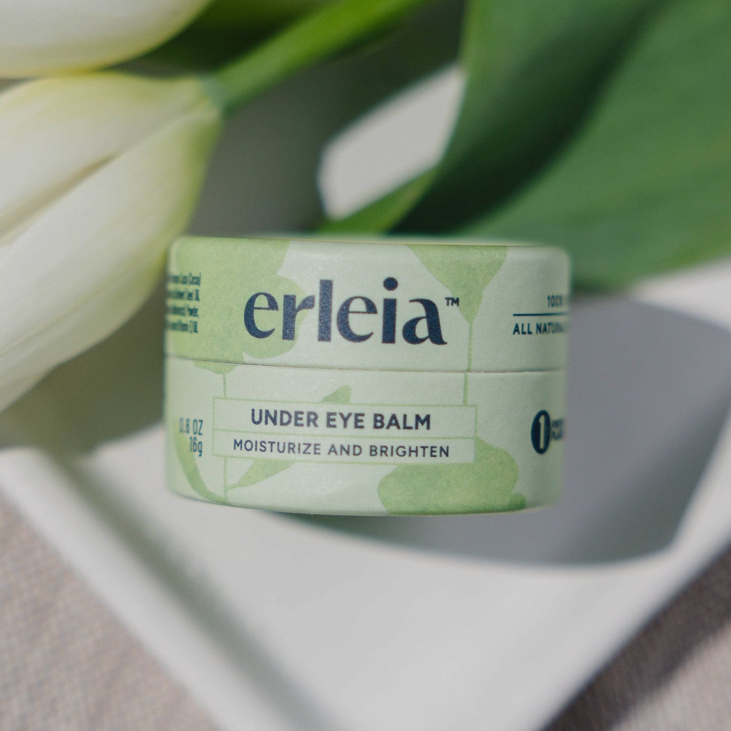 Erleia Under Eye Balm on a white dish with flowers