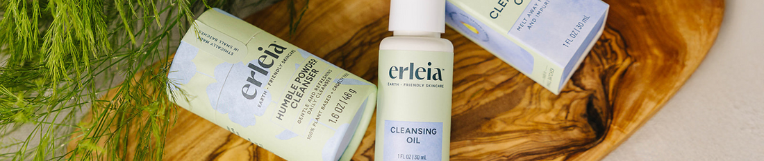 Erleia Humble Powder Cleanser and Cleansing Oil displayed on a wooden tray with fresh greenery