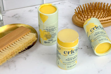 Erleia all-skin types face balm sits alongside a wooden brush and hairbrush, emphasizing a natural, earth-friendly skincare routine. 