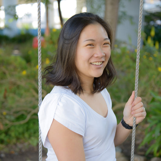Ada Chen, smiling while sitting on a swing