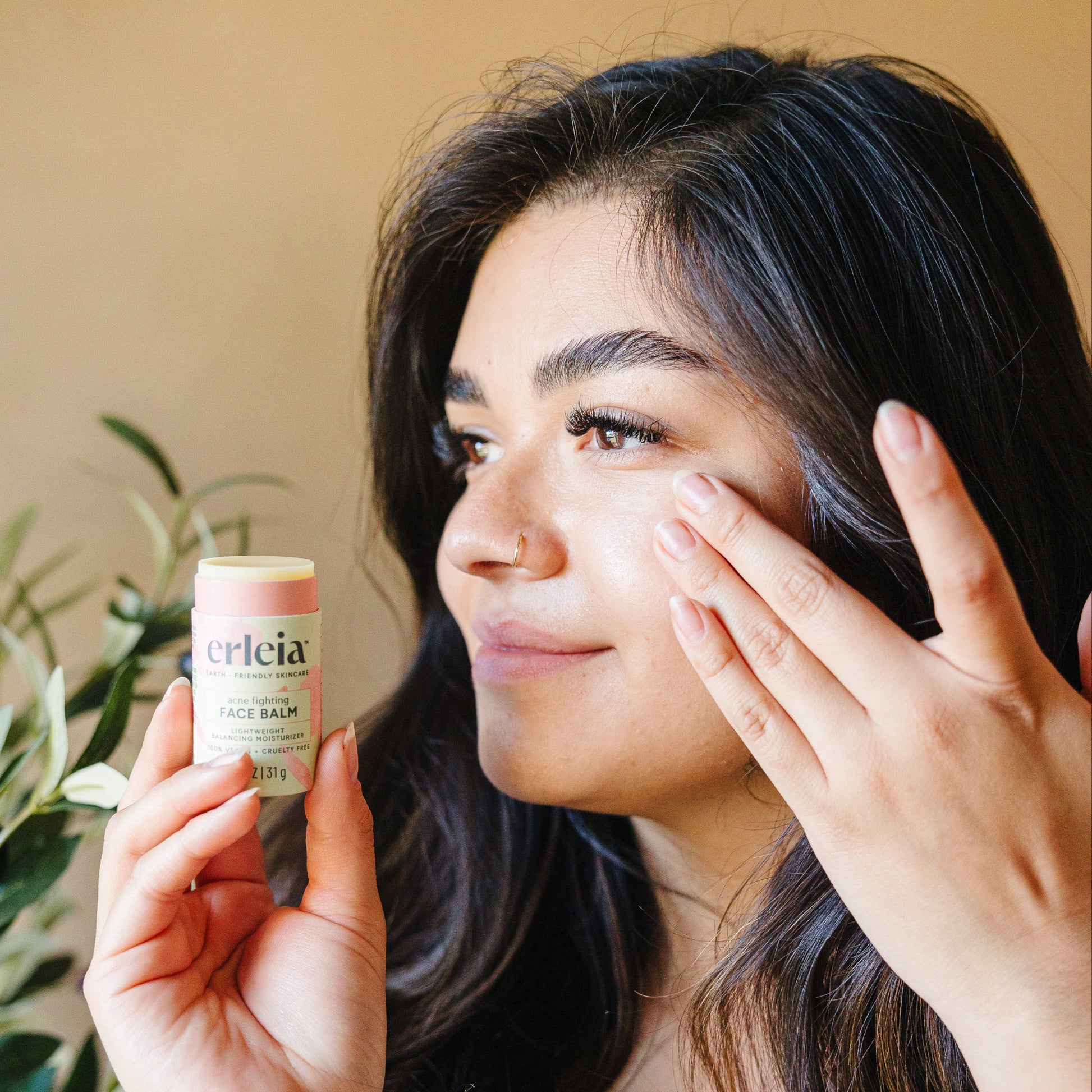 Erleia Acne Fighting Face Balm being applied with fingers to a light skinned brunette woman's face