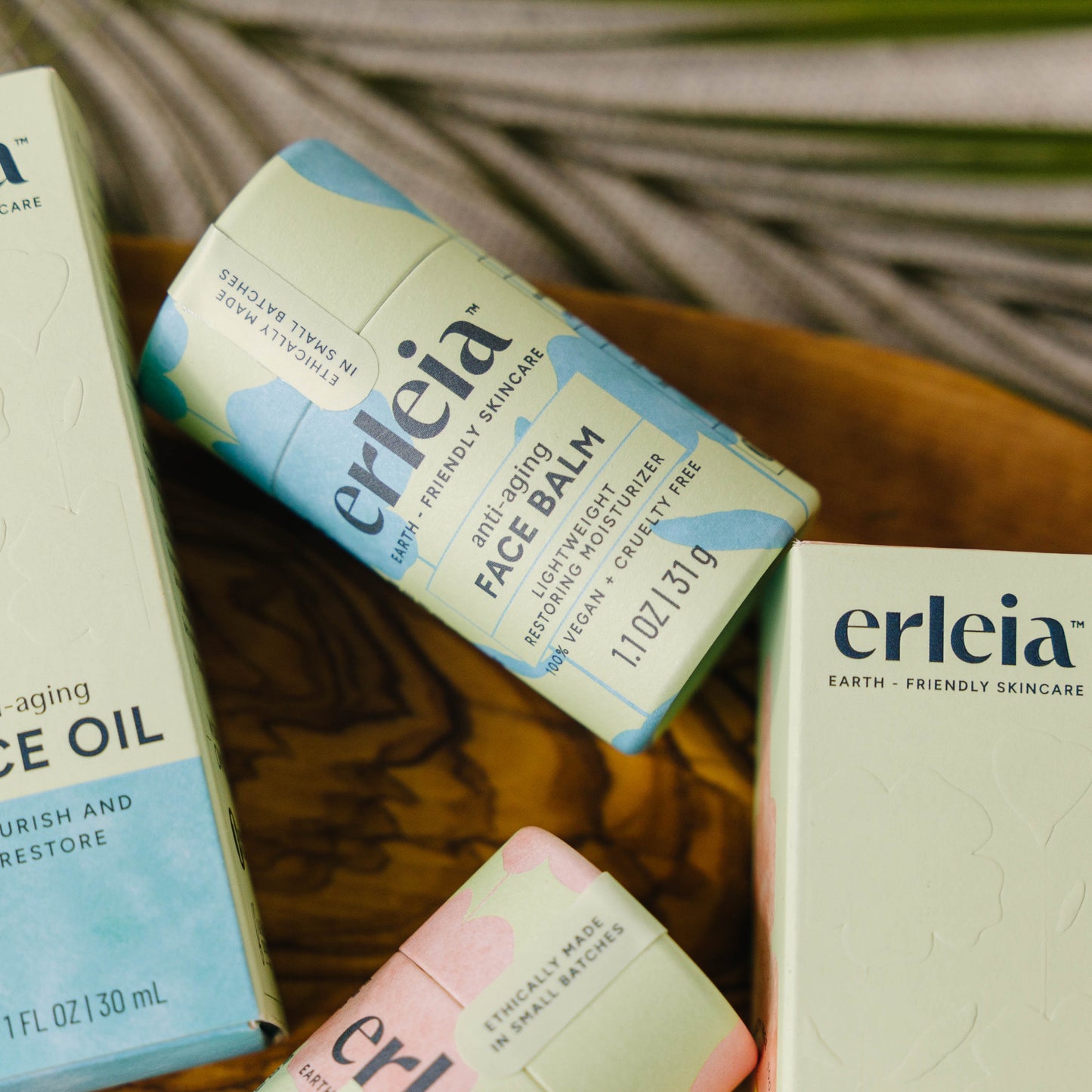 An Erleia Anti-Aging Face Balm surrounded by other Erleia skincare products on a wooden dish