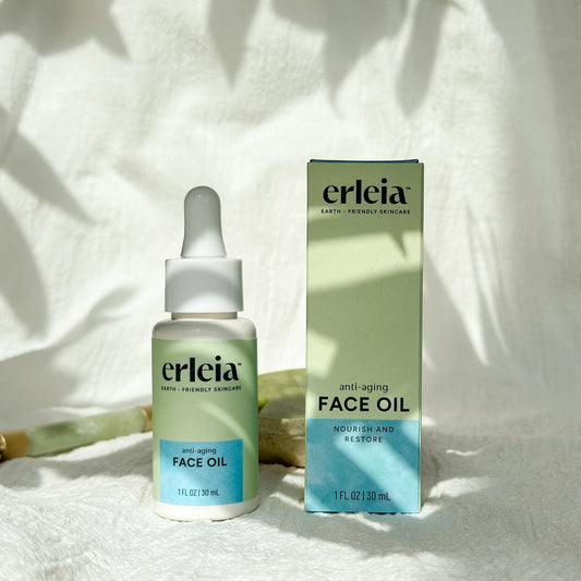 Erleia Face Oil - Anti-Aging Bottle and Box on a white warm background with shadows and jade skincare tools in the background