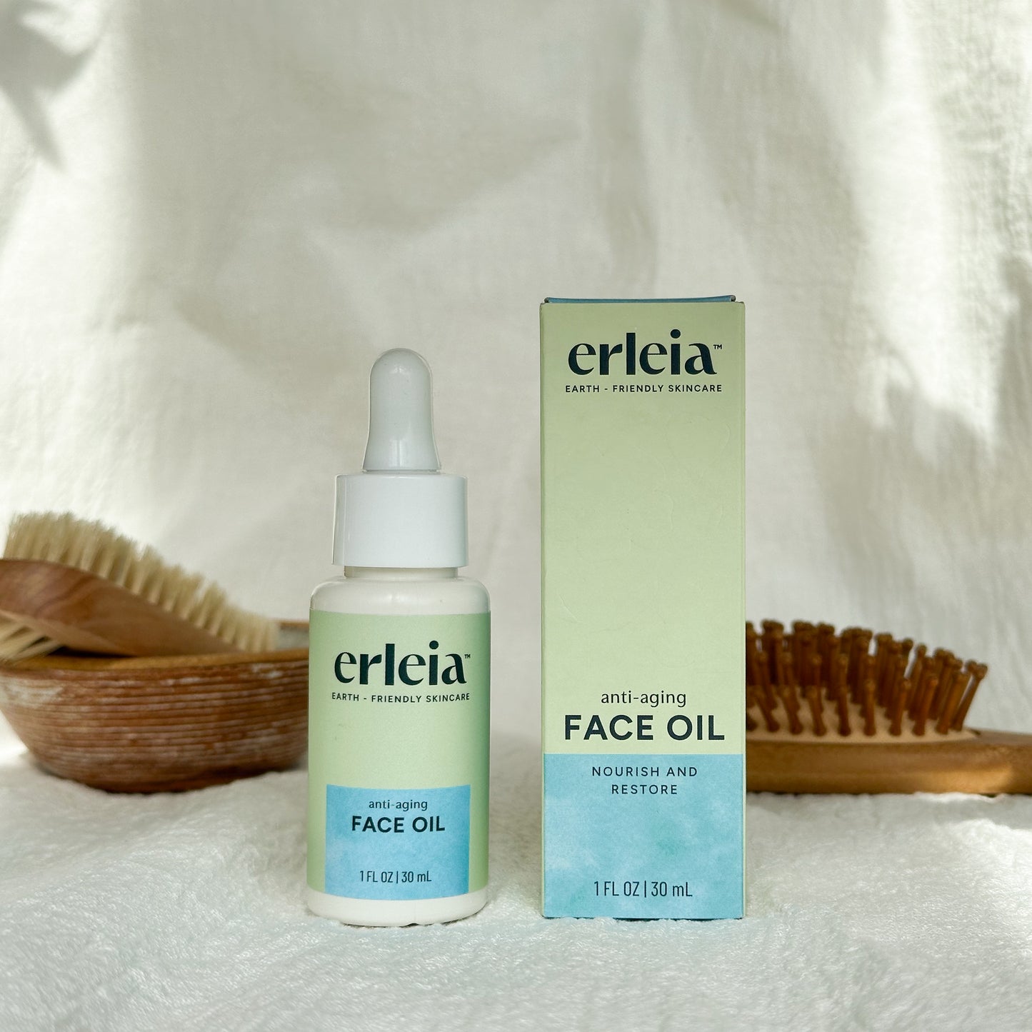 Erleia Face Oil - Anti-Aging Bottle and Box on a white warm background with shadows and bathroom items in the background