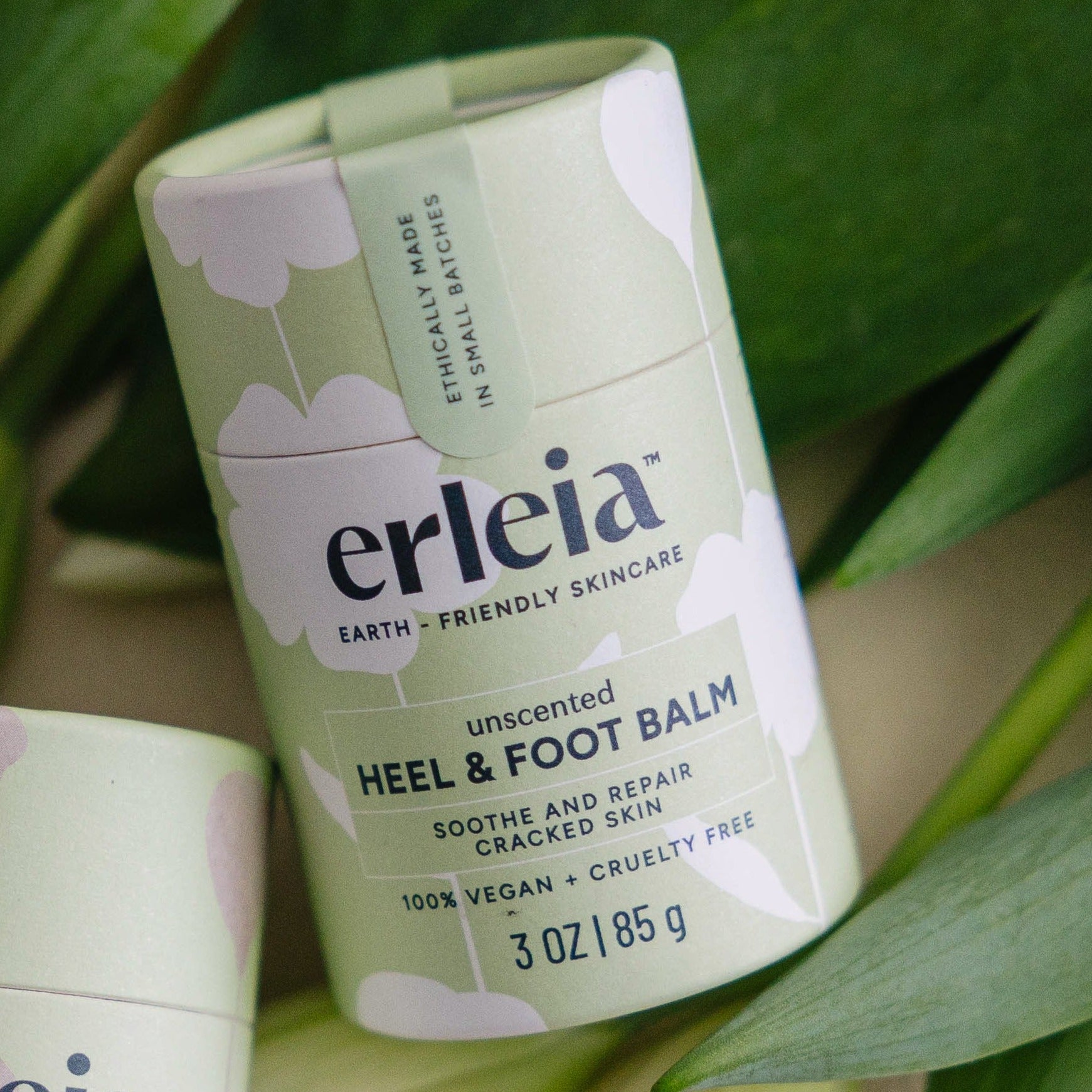 An Erleia unscented Heel & Foot Balm on green leaves