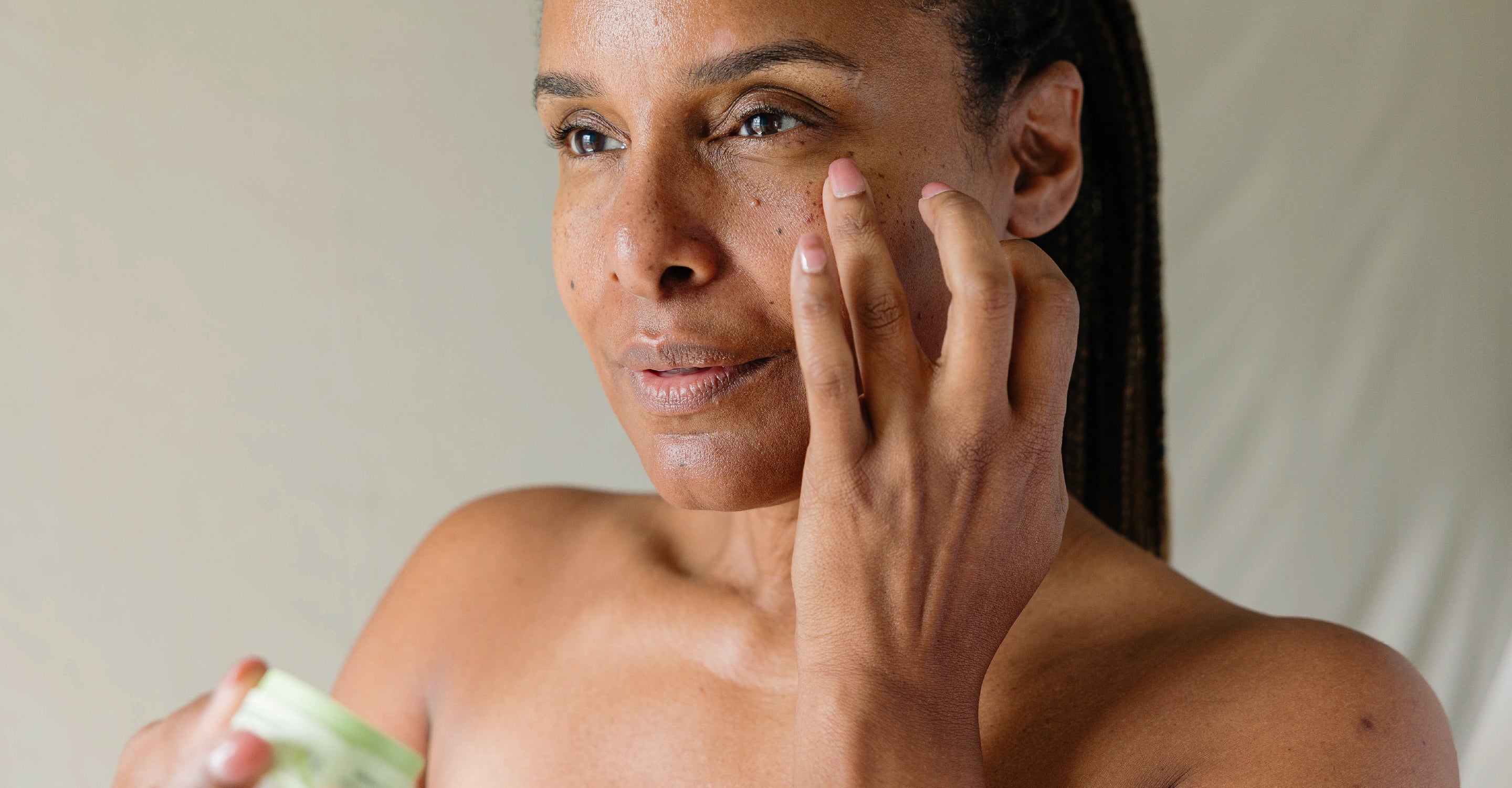 A Black woman applying Erleia Under Eye Balm to her undereye area
