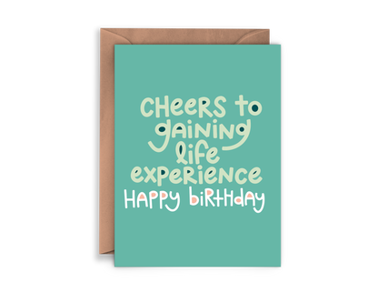 Greeting card reading "cheers to gaining life experience happy birthday"