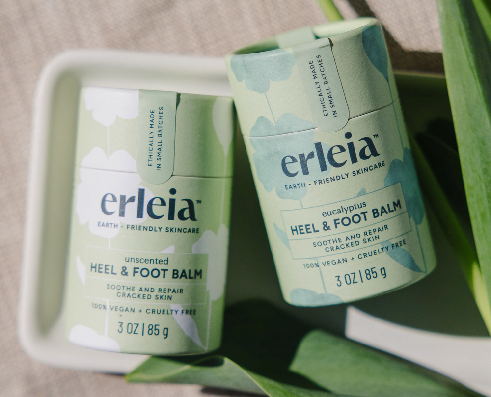 Erleia’s unscented and eucalyptus heel & foot balms are displayed side by side in green eco-friendly packaging, highlighting their 100% vegan and cruelty-free formulas for soothing and repairing cracked skin.