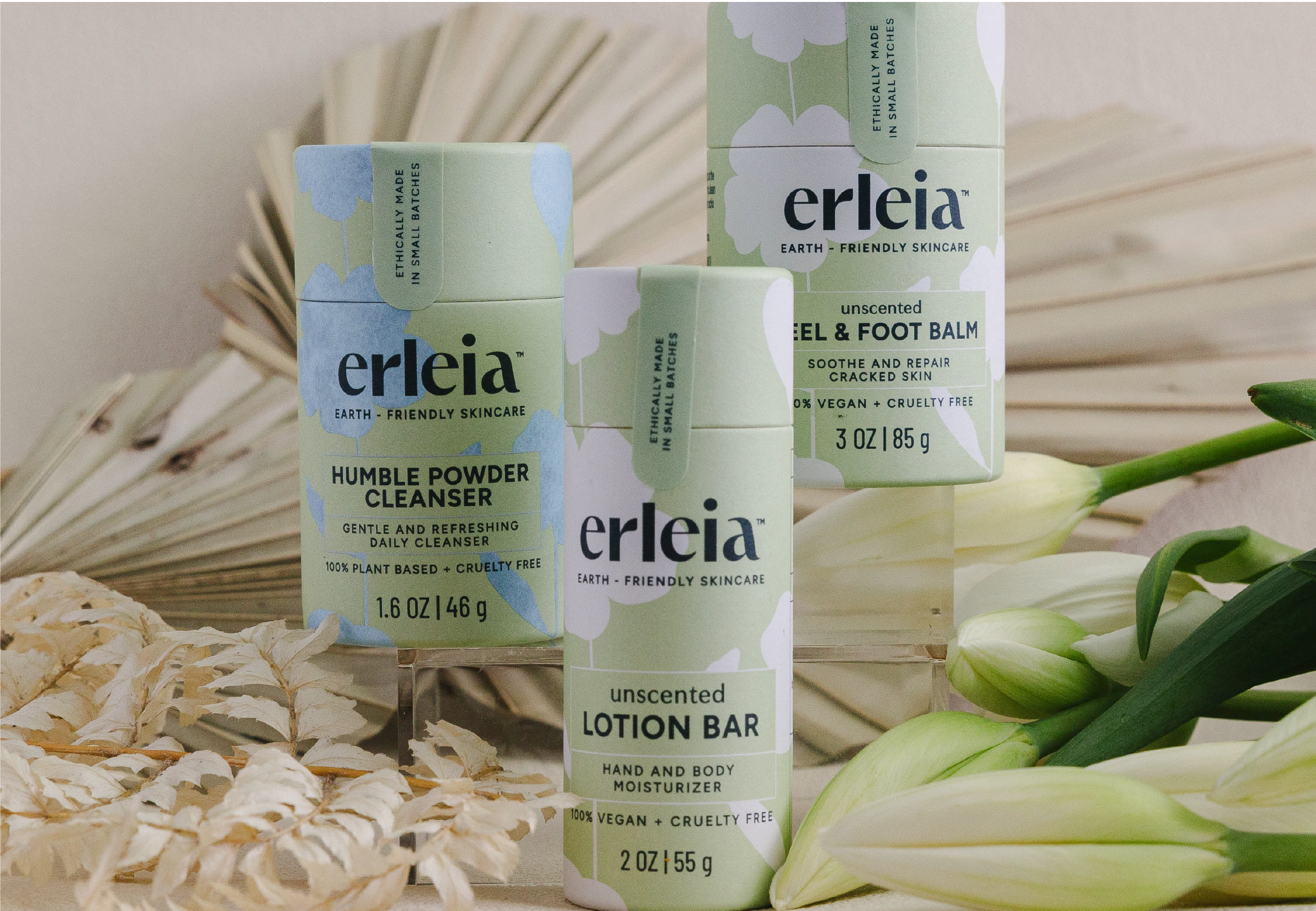 Erleia’s Humble Powder Cleanser, unscented lotion bar, and unscented heel & foot balm are displayed with natural decorative elements, highlighting their eco-friendly packaging and plant-based ingredients.